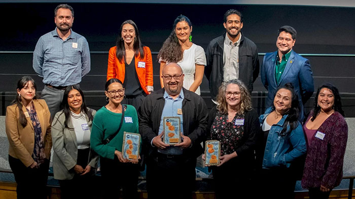 Group photo of Climate Leader Award recipients holding plaques at a recognition event with smiles and name tags.